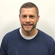 Male in a blue sweater against a beige background